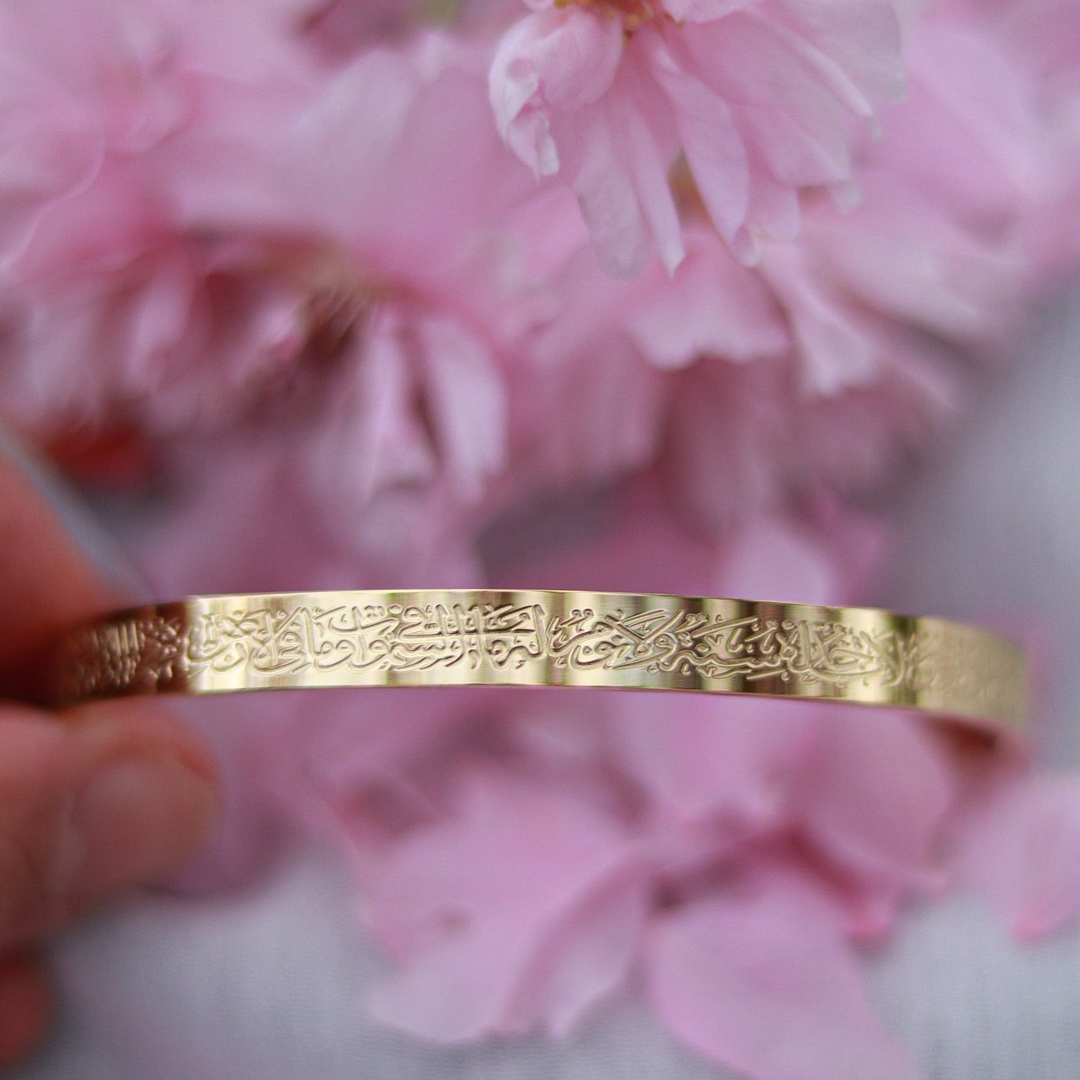 Ayatul Kursi Armreif in gold, Blumen im Hintergrund